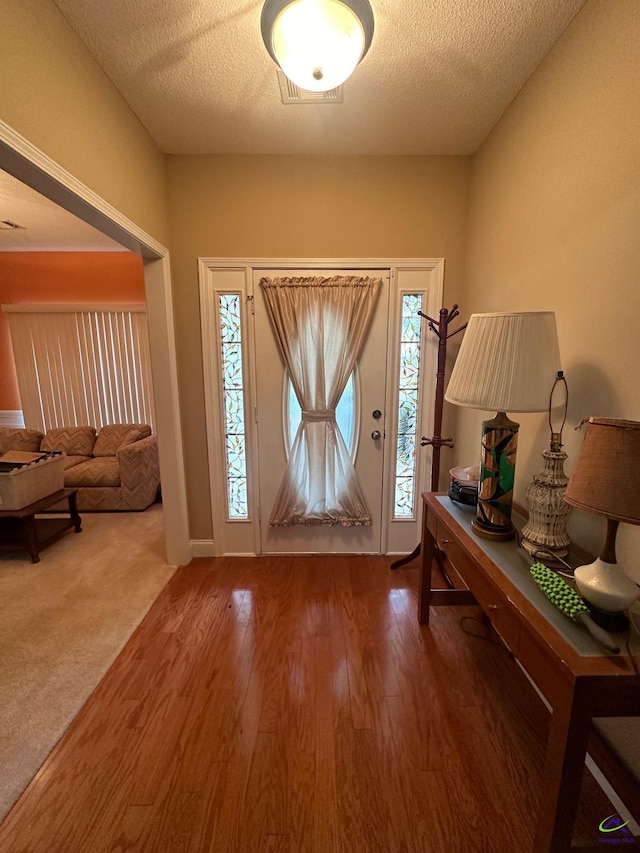 foyer entrance with hardwood / wood-style floors, a textured ceiling, and a healthy amount of sunlight