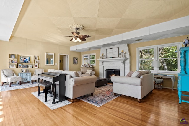 living room featuring ceiling fan, a fireplace, and hardwood / wood-style flooring