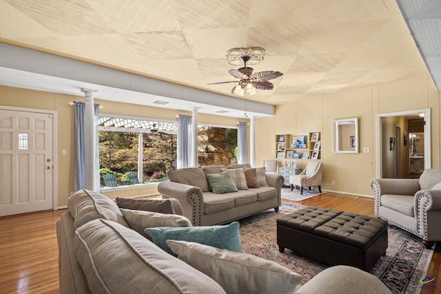 living room with decorative columns, ceiling fan, and hardwood / wood-style floors