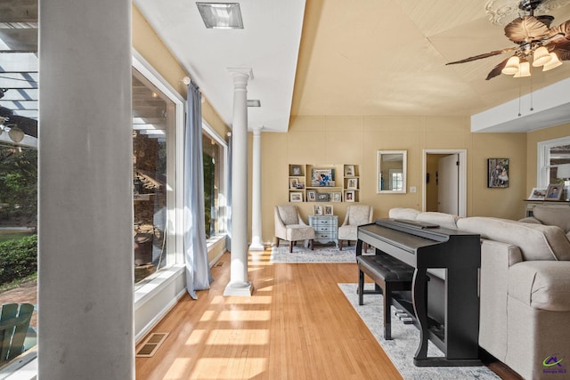 living room featuring wood-type flooring, decorative columns, and ceiling fan