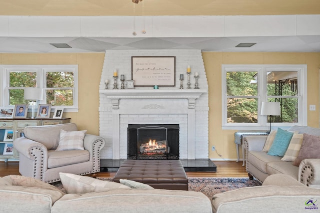 living room with hardwood / wood-style flooring and a brick fireplace