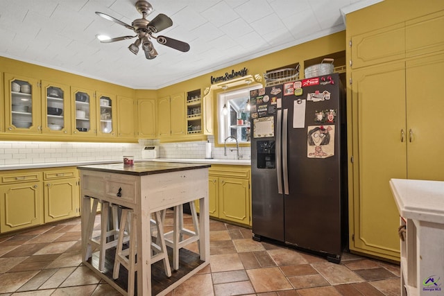 kitchen with backsplash, sink, ceiling fan, ornamental molding, and stainless steel fridge with ice dispenser