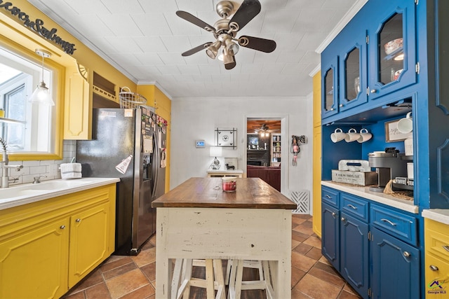 kitchen with blue cabinets, sink, ornamental molding, tasteful backsplash, and stainless steel fridge with ice dispenser