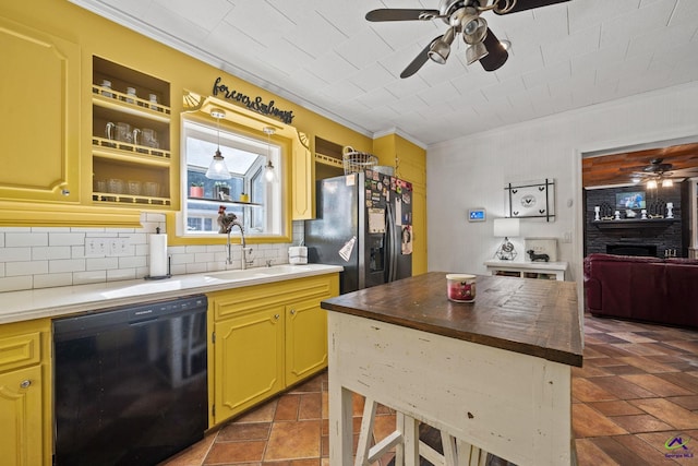 kitchen with decorative backsplash, stainless steel refrigerator with ice dispenser, sink, a fireplace, and black dishwasher