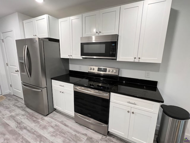 kitchen with stainless steel appliances, light hardwood / wood-style floors, and white cabinetry