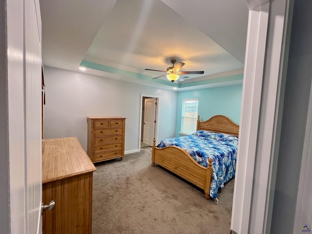 carpeted bedroom with ceiling fan and a tray ceiling