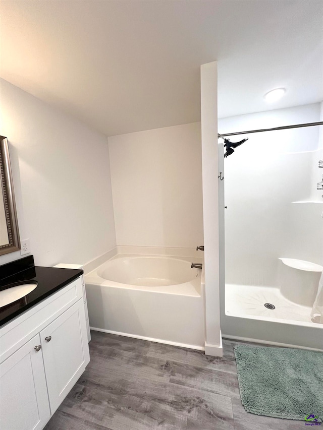 bathroom featuring wood-type flooring, vanity, and a tub to relax in