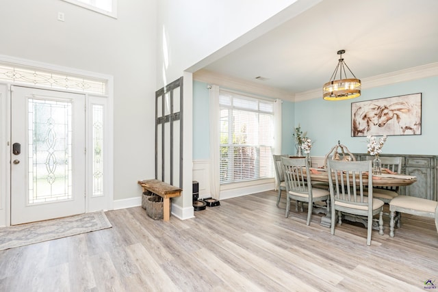 entryway with an inviting chandelier, crown molding, and light hardwood / wood-style flooring