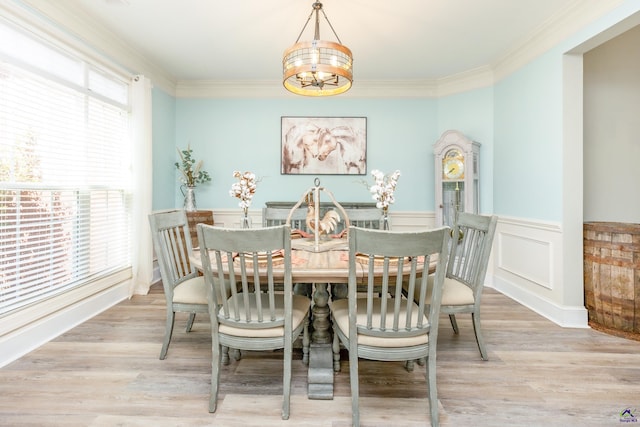 dining room with ornamental molding, light wood-type flooring, and a chandelier