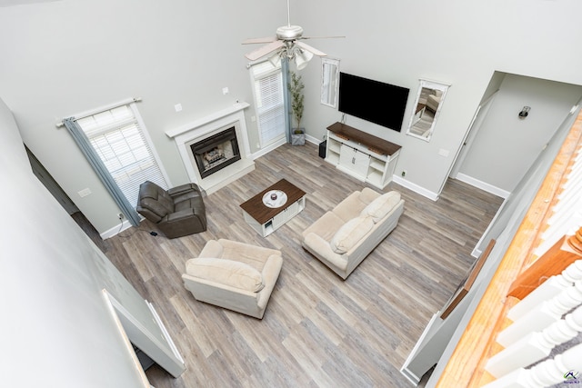 living room featuring hardwood / wood-style floors, ceiling fan, and a high ceiling