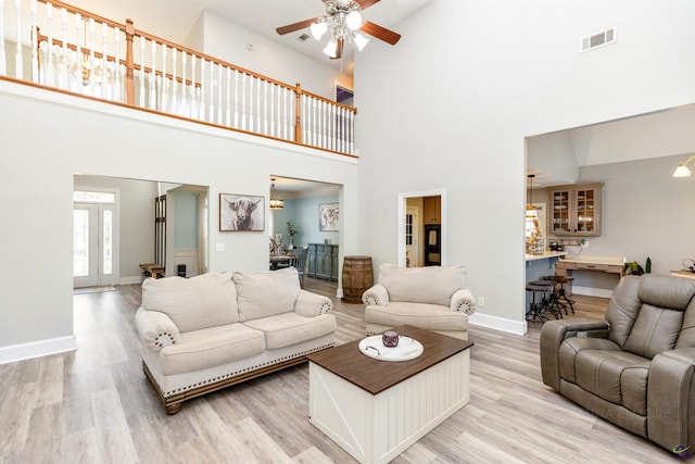 living room with french doors, a towering ceiling, ceiling fan, and light hardwood / wood-style floors