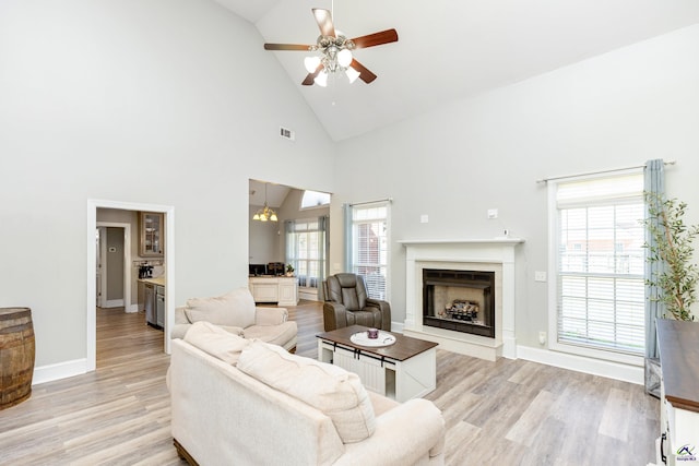 living room with high vaulted ceiling, a wealth of natural light, ceiling fan, and light hardwood / wood-style flooring