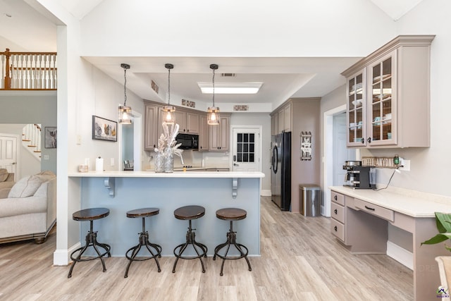 kitchen with a kitchen bar, black appliances, kitchen peninsula, and light hardwood / wood-style flooring