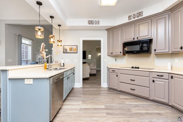 kitchen featuring black appliances, light wood-type flooring, decorative light fixtures, sink, and kitchen peninsula