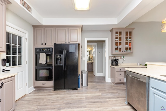 kitchen featuring black appliances, light hardwood / wood-style floors, and a raised ceiling