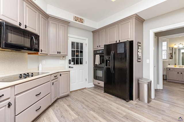 kitchen with decorative backsplash, light hardwood / wood-style flooring, and black appliances