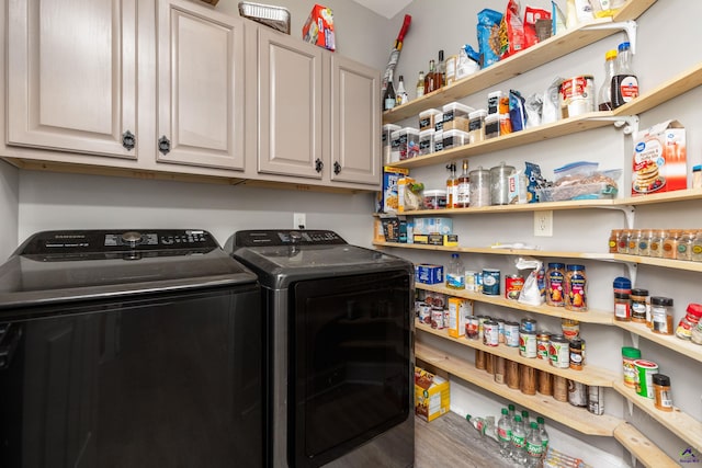 clothes washing area with cabinets and washer and clothes dryer