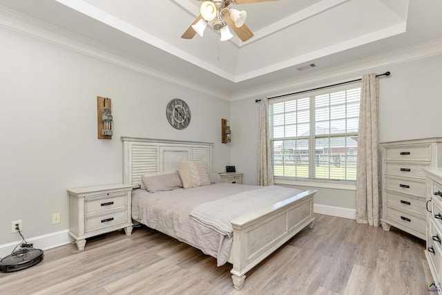 bedroom featuring light hardwood / wood-style floors, ceiling fan, a raised ceiling, and ornamental molding