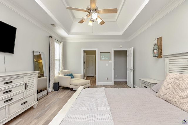 bedroom with ornamental molding, light hardwood / wood-style floors, ceiling fan, and a tray ceiling