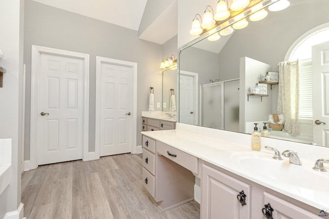 bathroom with vanity, vaulted ceiling, hardwood / wood-style flooring, and a shower with shower door