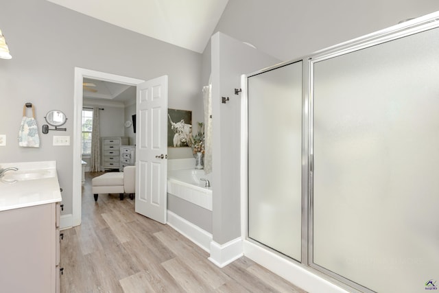 bathroom featuring wood-type flooring, plus walk in shower, vanity, and vaulted ceiling