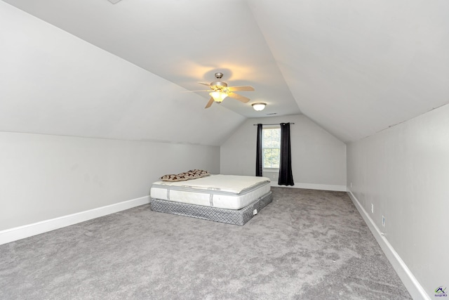 unfurnished bedroom with ceiling fan, carpet flooring, and vaulted ceiling