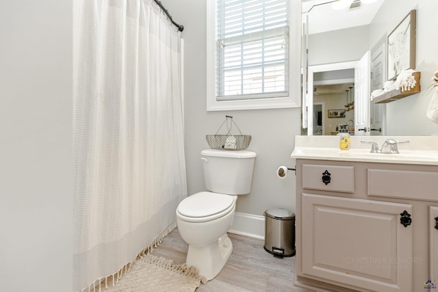 bathroom with toilet, vanity, hardwood / wood-style floors, and curtained shower