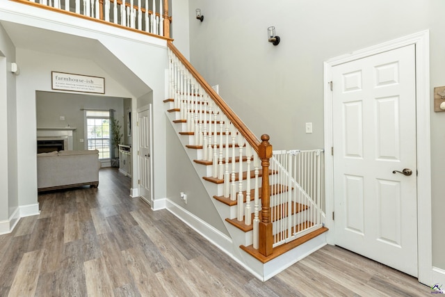 stairs with hardwood / wood-style floors and a high ceiling