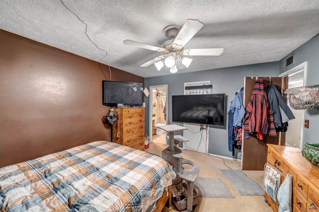 carpeted bedroom featuring a textured ceiling, ceiling fan, and ensuite bath