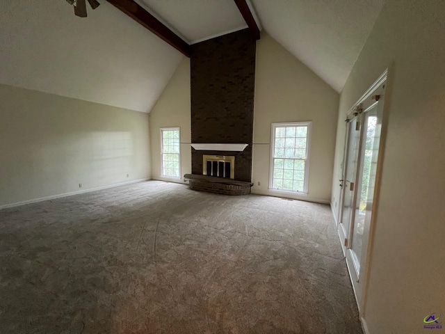 unfurnished living room featuring carpet floors, high vaulted ceiling, ceiling fan, beam ceiling, and a fireplace