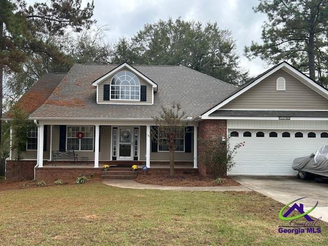 view of front of house featuring a garage, a front yard, and a porch