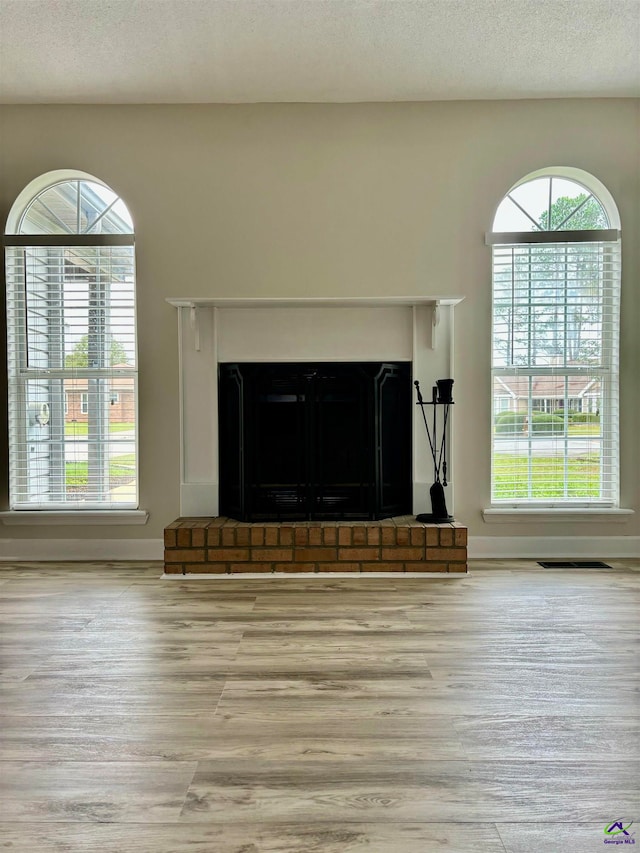 room details featuring hardwood / wood-style floors, a textured ceiling, and a brick fireplace