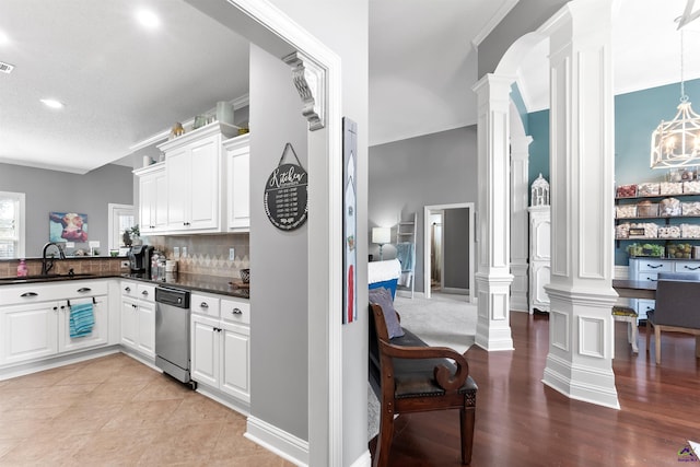 kitchen featuring white cabinets, decorative backsplash, stainless steel dishwasher, and sink