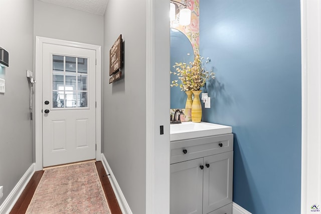 doorway to outside with sink, dark wood-type flooring, and a textured ceiling