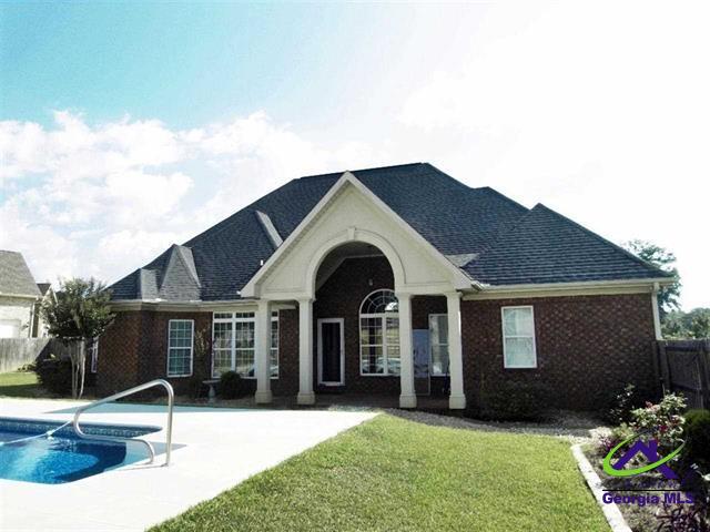 rear view of house featuring a fenced in pool and a lawn