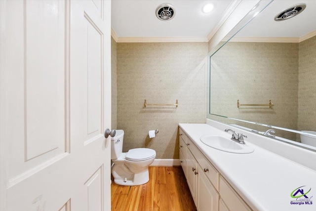 bathroom with wood-type flooring, vanity, toilet, and ornamental molding