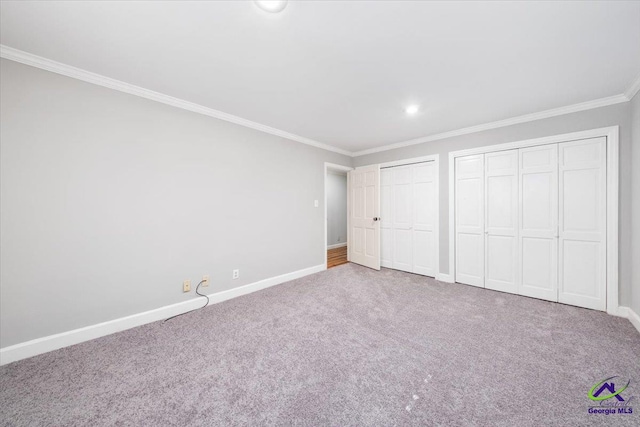 unfurnished bedroom featuring multiple closets, crown molding, and carpet floors