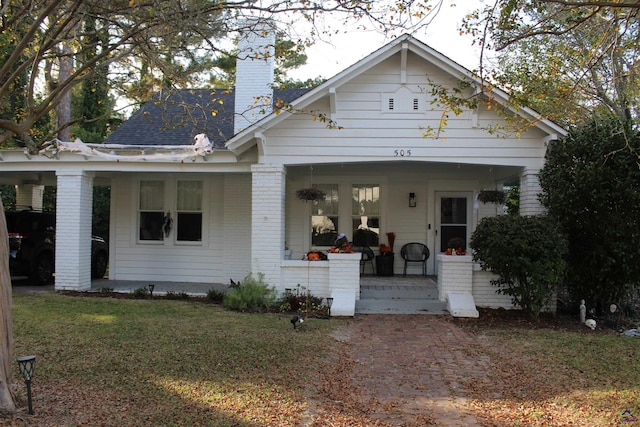 view of front of home with covered porch and a front lawn