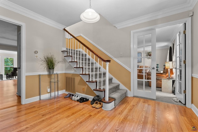 stairway with wood-type flooring and crown molding