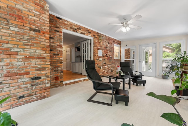 interior space with ceiling fan, ornamental molding, brick wall, and light hardwood / wood-style floors