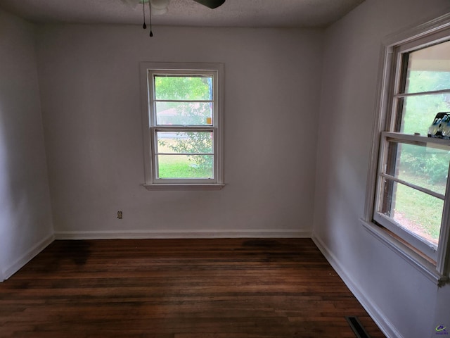 spare room with a textured ceiling, dark hardwood / wood-style floors, plenty of natural light, and ceiling fan