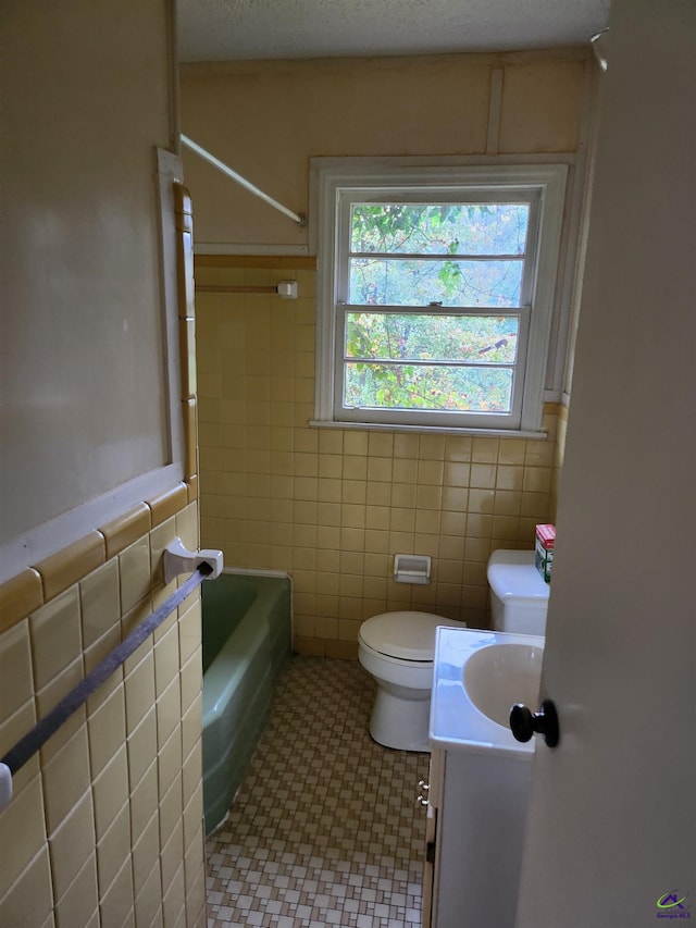 bathroom with vanity, tile patterned floors, toilet, tile walls, and a textured ceiling