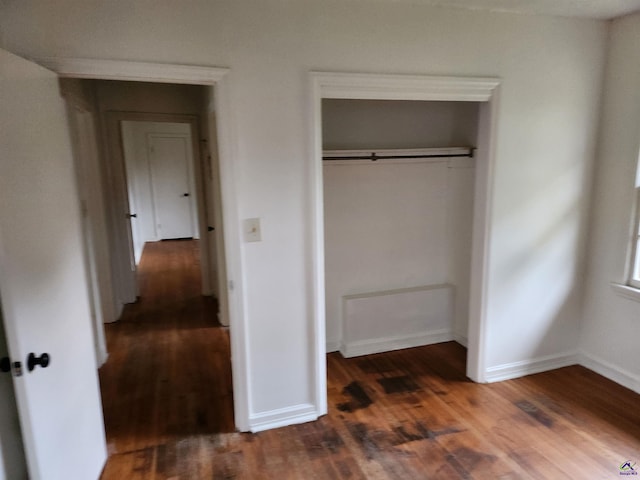 unfurnished bedroom with dark hardwood / wood-style flooring and a closet