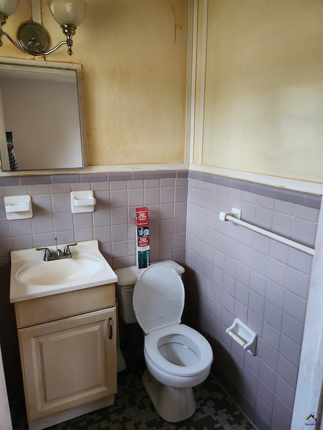 bathroom with vanity, toilet, and tile walls