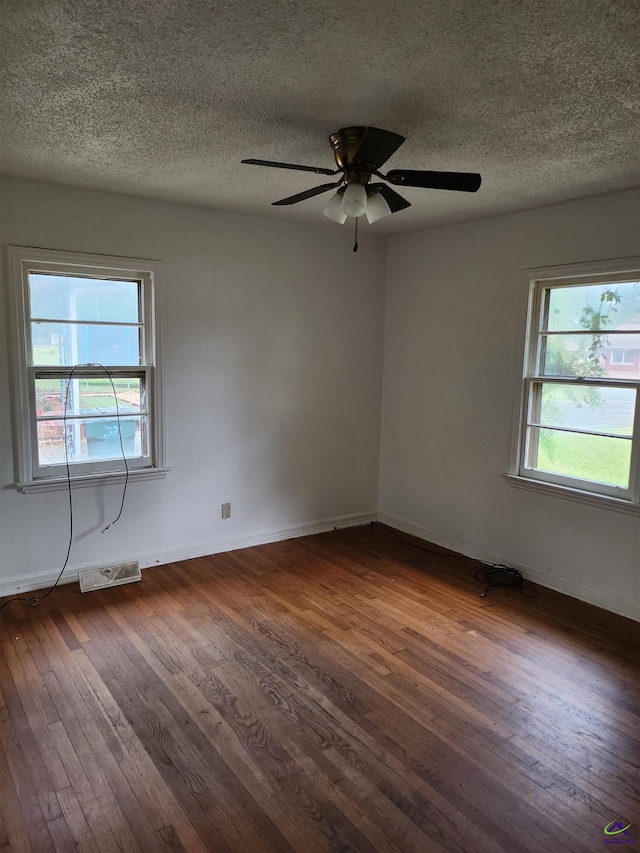 spare room featuring a textured ceiling, dark hardwood / wood-style flooring, and a wealth of natural light