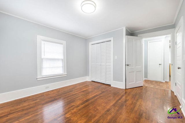 unfurnished bedroom with hardwood / wood-style floors, crown molding, and a closet