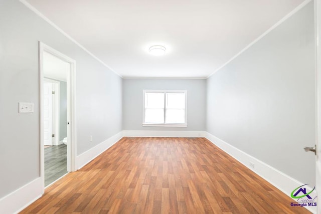 spare room with wood-type flooring and crown molding