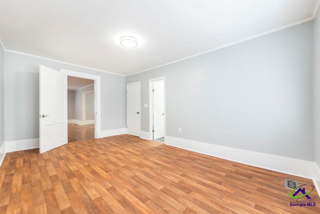 empty room featuring ornamental molding and light wood-type flooring