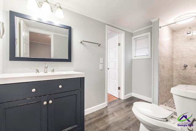 bathroom with vanity, crown molding, toilet, a tile shower, and wood-type flooring