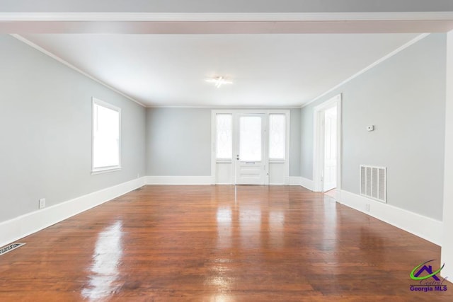 empty room featuring hardwood / wood-style floors, ornamental molding, and a wealth of natural light